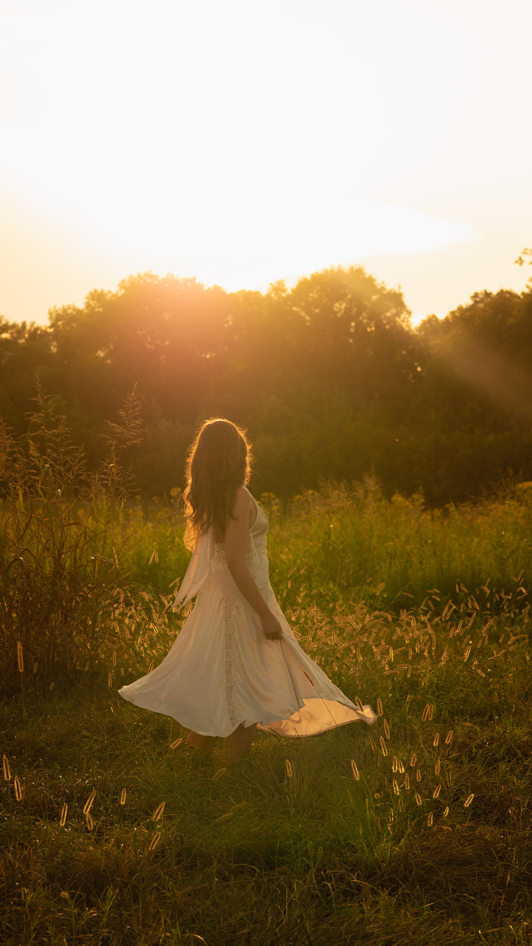 A girl twirling in a sundress through a sunlit meadow